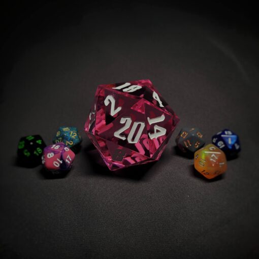 An extra large pink transparent d20 die with white numbers sitting in the middle of 6 smaller d20 dice.